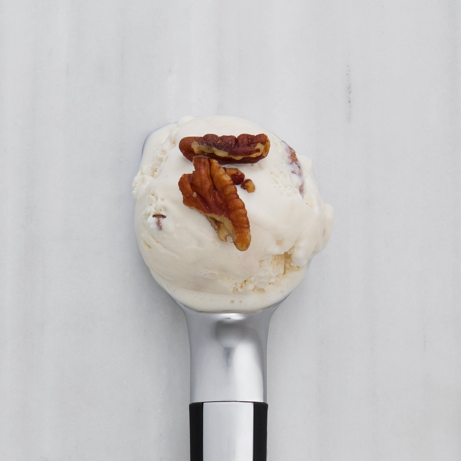 Ice cream scoop with a scoop of vanilla ice cream and pecans 