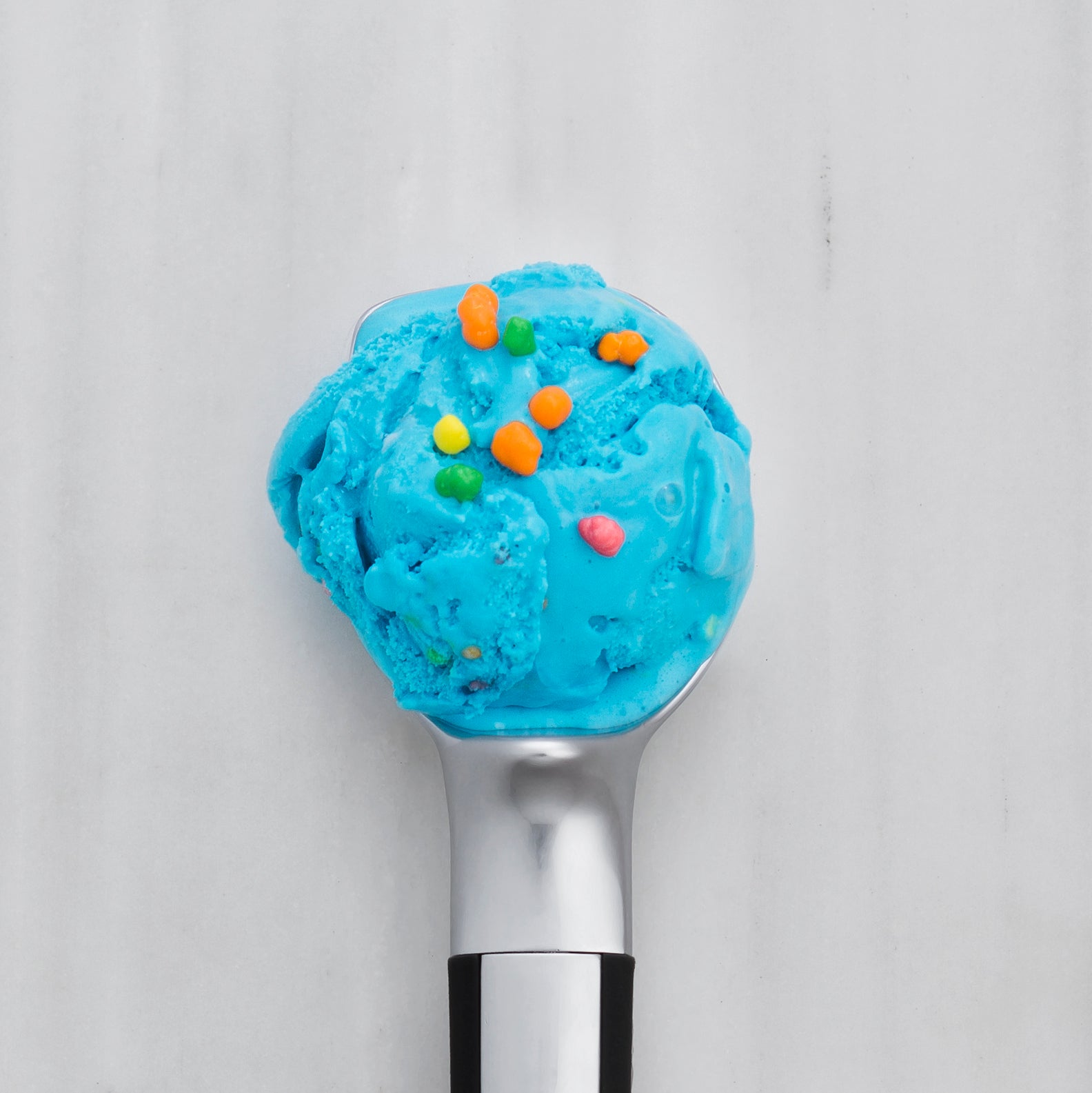 Blue ice cream scoop with colorful sprinkles on a white background